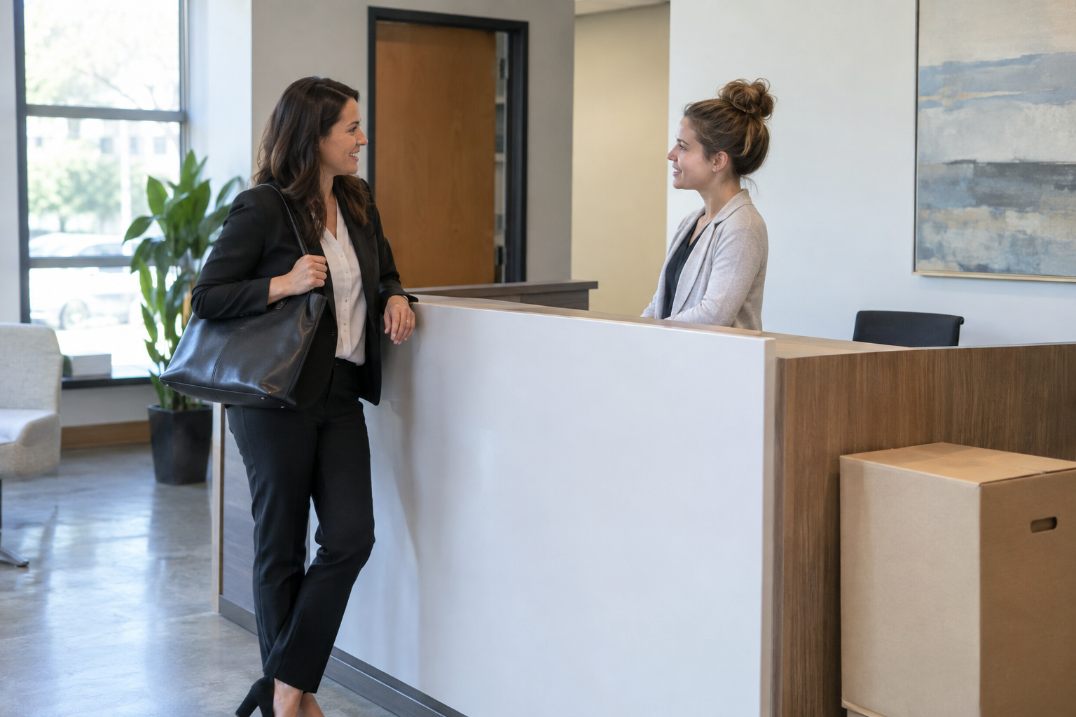 Real estate agent speaking with a colleague at an office reception desk.